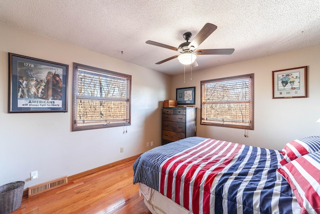 bedroom featuring ceiling fan, wood-type flooring, and a textured ceiling