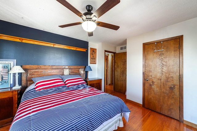 bedroom with hardwood / wood-style floors, a closet, ceiling fan, and a textured ceiling