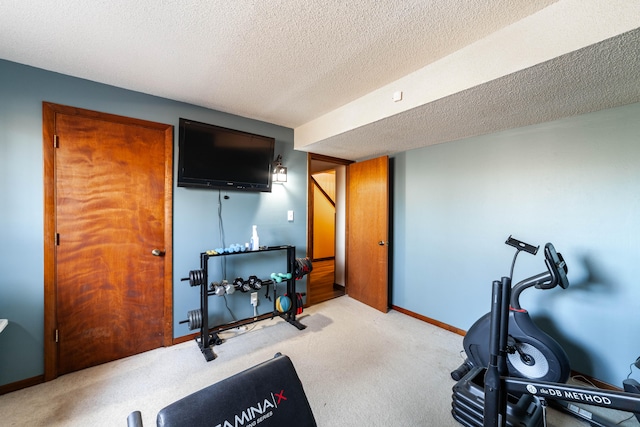 workout area featuring light carpet and a textured ceiling