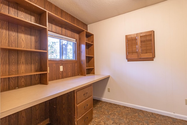 unfurnished office with wood walls and a textured ceiling