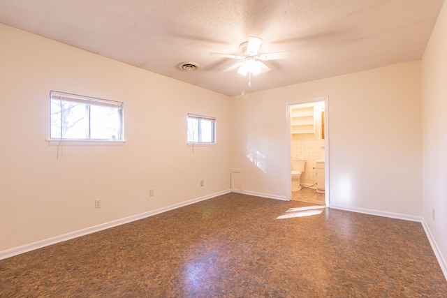 unfurnished room featuring ceiling fan, a textured ceiling, and tile walls