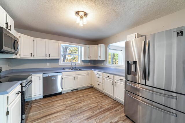 kitchen with white cabinets, stainless steel appliances, and light hardwood / wood-style floors