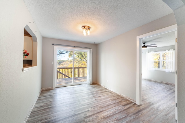 unfurnished room featuring ceiling fan, light wood-type flooring, and a textured ceiling