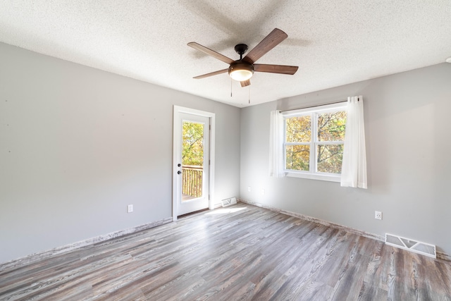 empty room featuring a textured ceiling, light hardwood / wood-style floors, a wealth of natural light, and ceiling fan