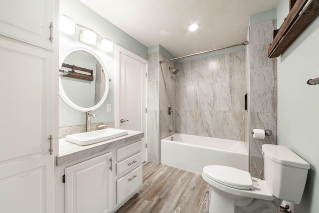 full bathroom with vanity, tiled shower / bath, toilet, a textured ceiling, and wood-type flooring