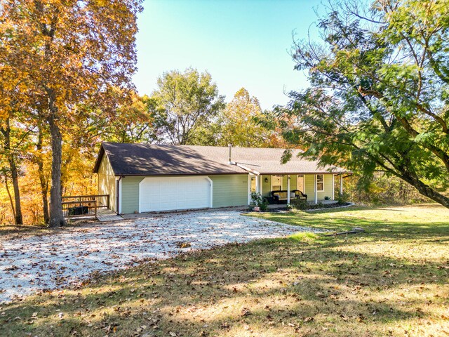 single story home featuring a porch, a garage, and a front lawn