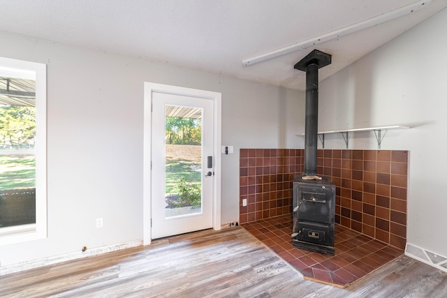 doorway to outside featuring a wood stove, tile walls, and hardwood / wood-style flooring