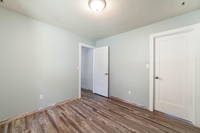 unfurnished bedroom featuring a textured ceiling and dark wood-type flooring