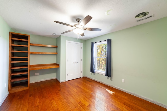 unfurnished bedroom featuring a textured ceiling, hardwood / wood-style flooring, and ceiling fan