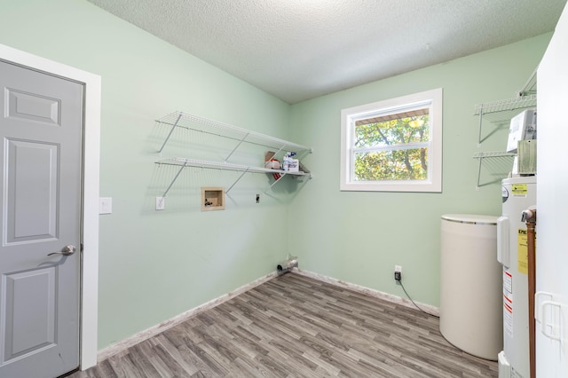 washroom featuring washer hookup, hookup for an electric dryer, water heater, a textured ceiling, and light wood-type flooring