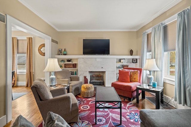 living room featuring light hardwood / wood-style floors, crown molding, and a premium fireplace