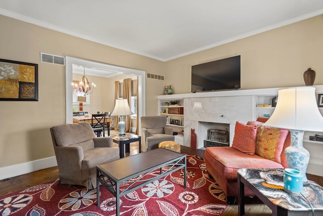 living room featuring dark hardwood / wood-style flooring, an inviting chandelier, crown molding, and a premium fireplace