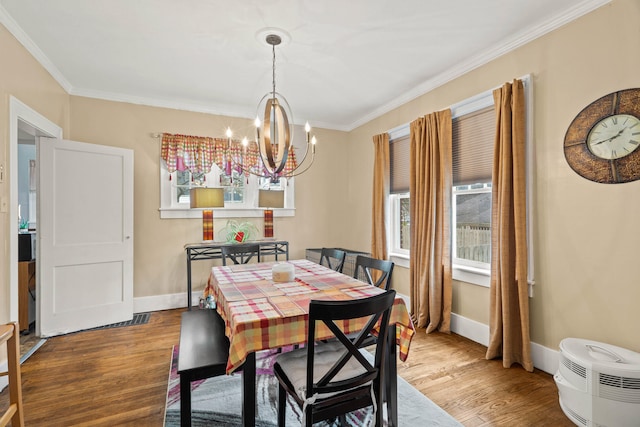 dining area with hardwood / wood-style floors, an inviting chandelier, and crown molding