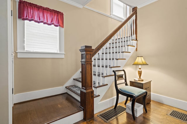 stairs with a healthy amount of sunlight, wood-type flooring, and crown molding