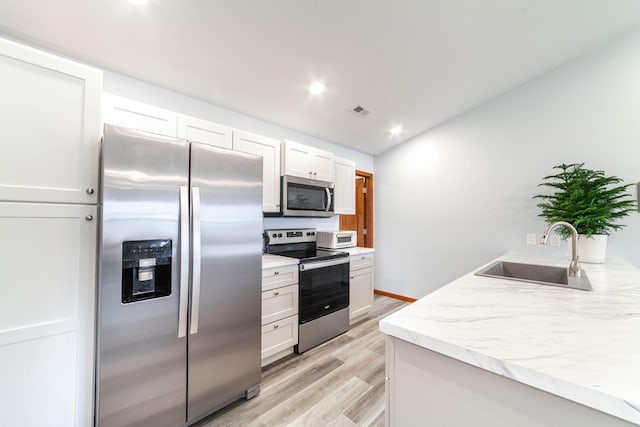 kitchen featuring appliances with stainless steel finishes, light hardwood / wood-style flooring, white cabinetry, and sink