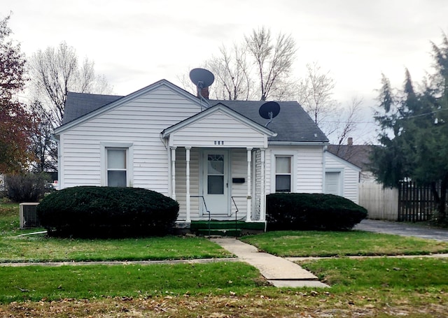 bungalow-style house with central air condition unit and a front yard