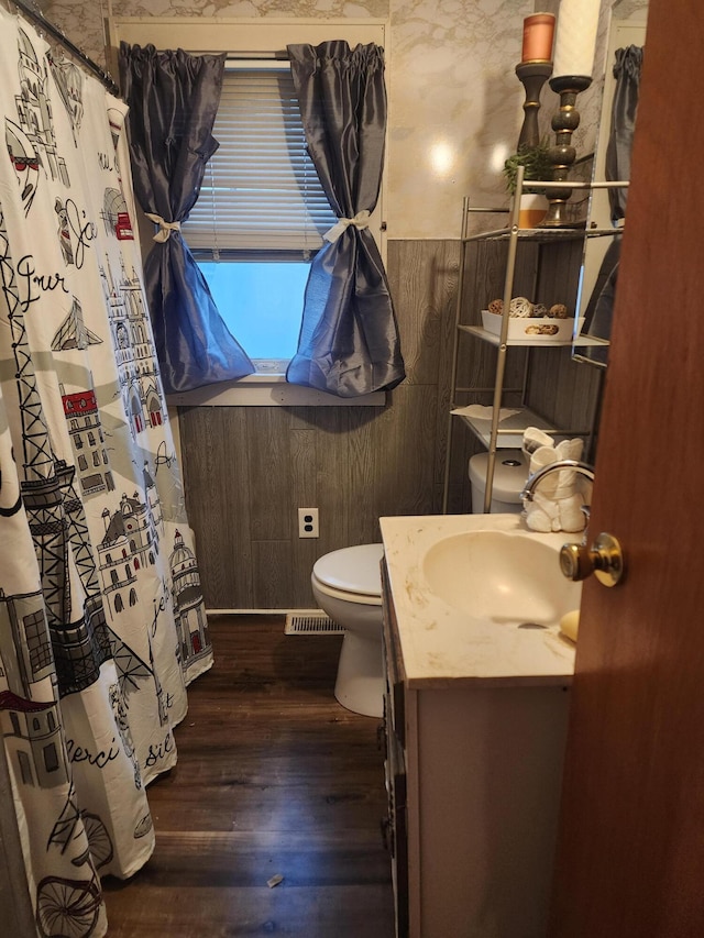 bathroom with vanity, wood walls, toilet, and wood-type flooring