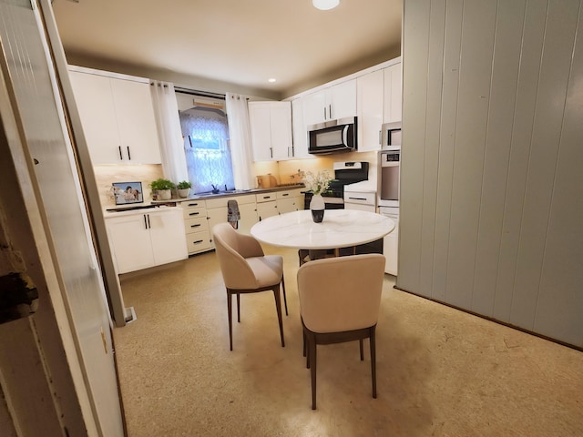 kitchen featuring white cabinets, wooden walls, sink, and appliances with stainless steel finishes