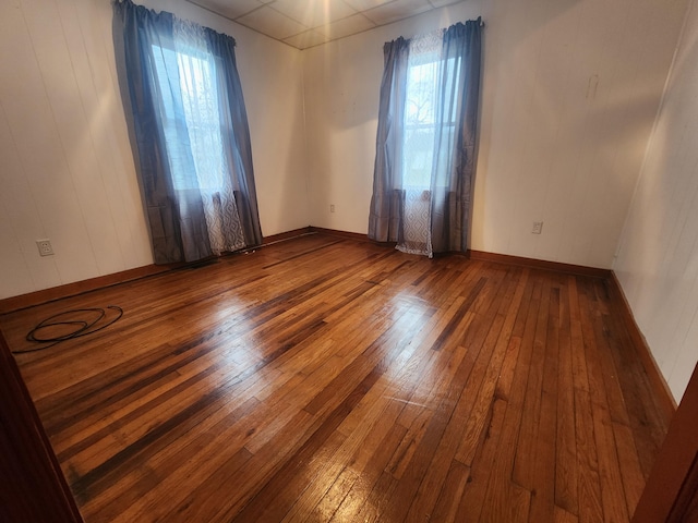 empty room featuring wood-type flooring and a paneled ceiling