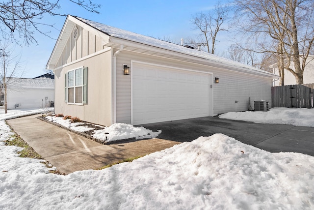 view of snow covered exterior featuring a garage and central AC unit