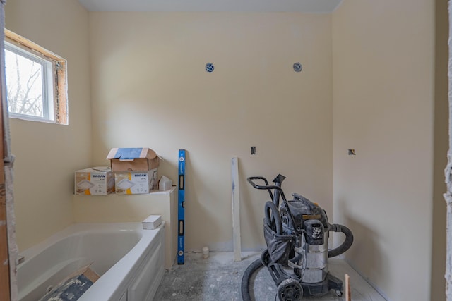 bathroom with concrete flooring and a tub