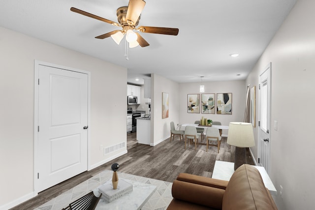 living room featuring ceiling fan and dark hardwood / wood-style floors