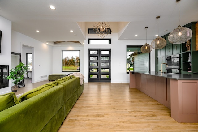 living room with a chandelier, french doors, light wood-type flooring, and sink