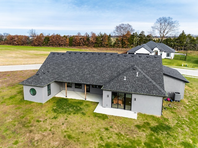 rear view of property featuring a patio, central air condition unit, and a lawn