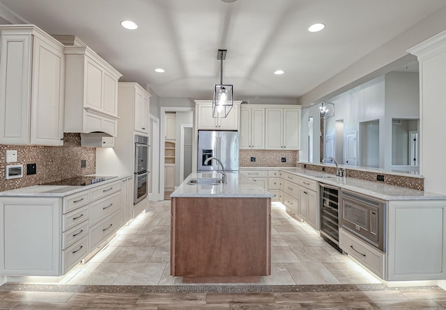 kitchen with pendant lighting, sink, tasteful backsplash, stainless steel appliances, and beverage cooler