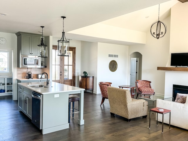 kitchen with hanging light fixtures, sink, a kitchen island with sink, and appliances with stainless steel finishes