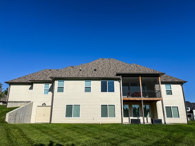 rear view of property featuring a lawn and a balcony