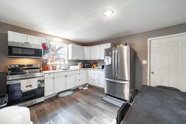 kitchen featuring white cabinetry, dark wood-type flooring, a textured ceiling, and appliances with stainless steel finishes