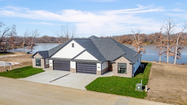 view of front of house with a front yard, a water view, and a garage