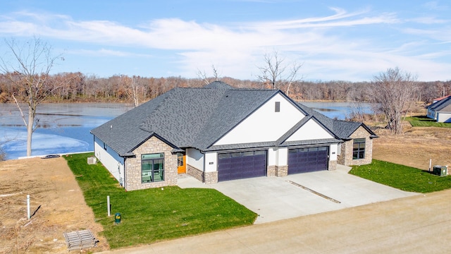 view of front of house with a front yard, a water view, and a garage