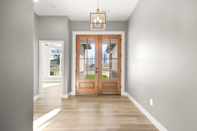 doorway to outside with french doors, light hardwood / wood-style floors, and an inviting chandelier