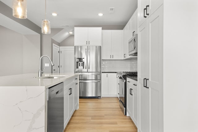 kitchen with appliances with stainless steel finishes, white cabinetry, hanging light fixtures, and sink