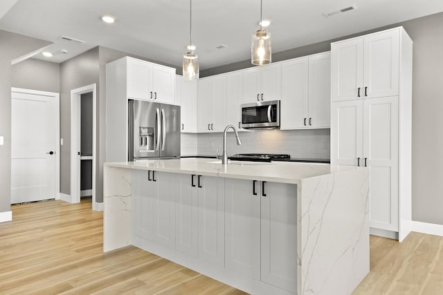 kitchen featuring a center island with sink, white cabinets, light hardwood / wood-style flooring, and appliances with stainless steel finishes