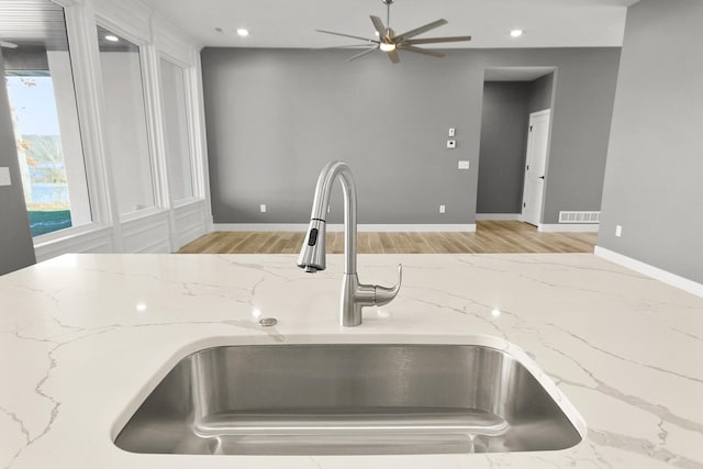 kitchen with ceiling fan, light hardwood / wood-style floors, light stone countertops, and sink