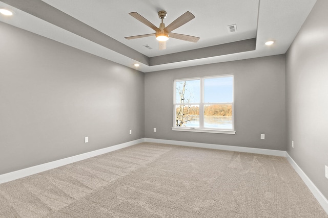 empty room featuring carpet, ceiling fan, and a tray ceiling