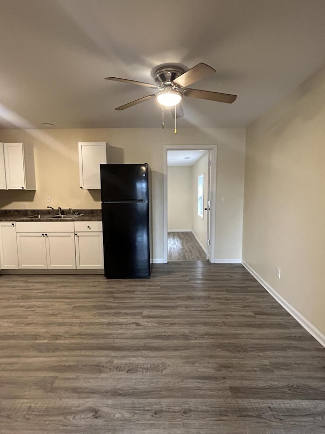 kitchen with white cabinetry, sink, ceiling fan, dark wood-type flooring, and black fridge