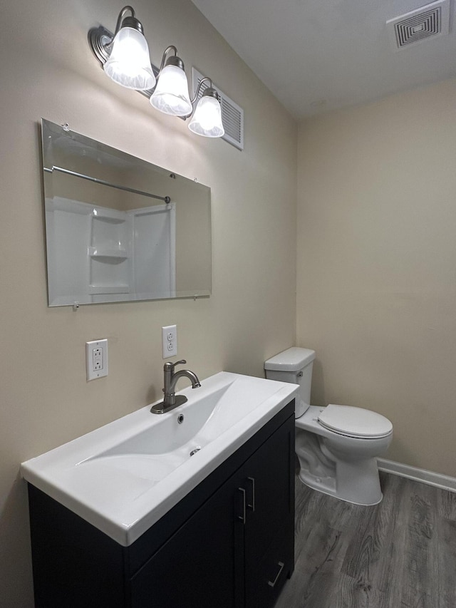 bathroom with walk in shower, hardwood / wood-style floors, vanity, and toilet