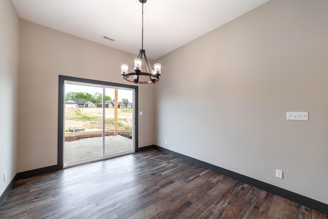 spare room with dark hardwood / wood-style floors and a notable chandelier