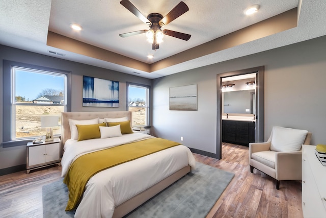 bedroom featuring hardwood / wood-style flooring, ceiling fan, connected bathroom, and multiple windows