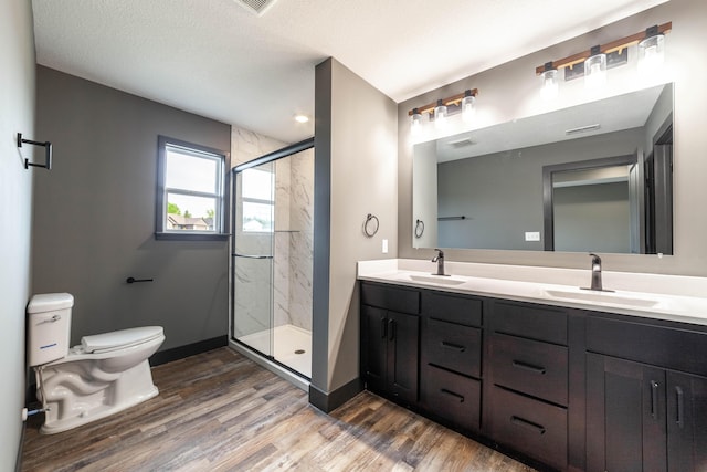 bathroom featuring a textured ceiling, vanity, hardwood / wood-style flooring, toilet, and a shower with shower door