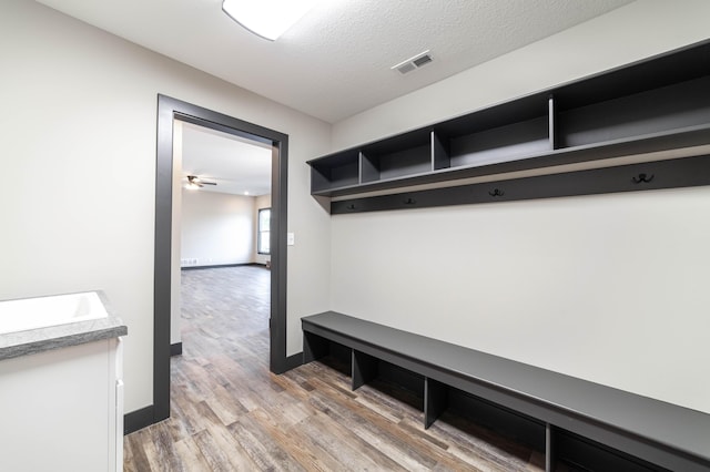 mudroom with a textured ceiling, light hardwood / wood-style flooring, ceiling fan, and sink