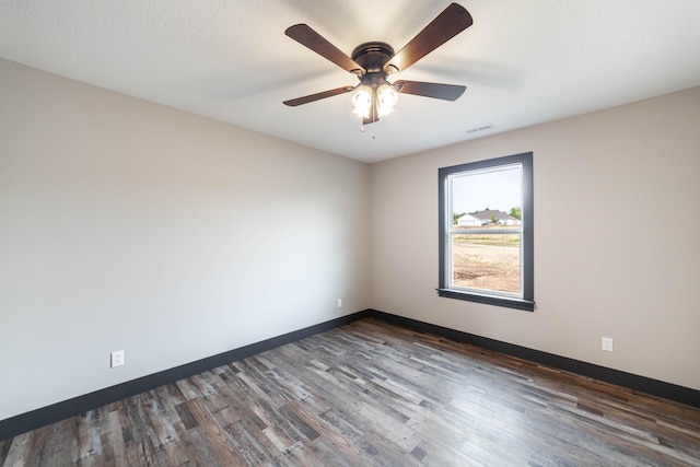 empty room with a textured ceiling, dark hardwood / wood-style flooring, and ceiling fan