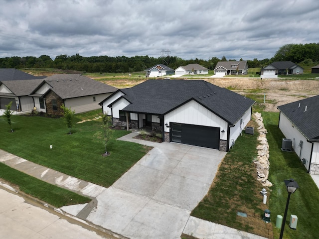 view of front facade featuring central air condition unit, a front lawn, and a garage