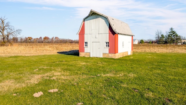 view of outbuilding with a lawn and a rural view