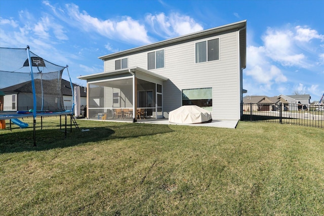 rear view of house featuring a sunroom, a yard, a patio, and a trampoline