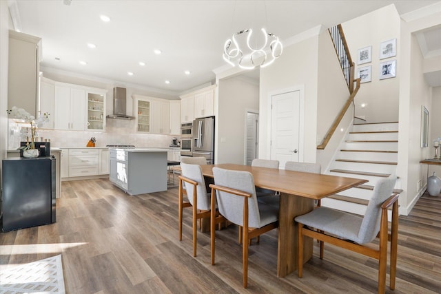 dining space with light wood-type flooring, crown molding, and a chandelier